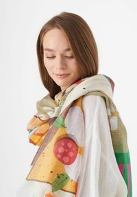 Écharpe légère présentant un motif abstrait coloré avec des cercles et des formes en orange, vert et rouge sur un fond beige.