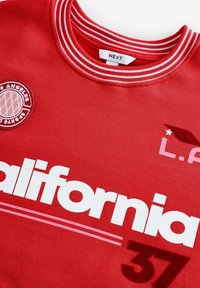 Rød bomulds sweatshirt med ribbet rund halsudskæring, broderet Los Angeles Sports Club-logo og hvid tekst, der står "California 37."