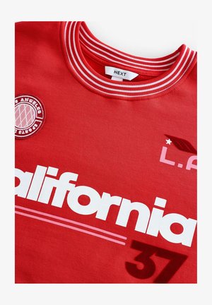 Tricou din bumbac roșu, cu guler pe gât ribbat, logo brodat al Los Angeles Sports Club și text imprimat alb care spune "California 37."