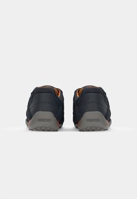 Dark blue footwear with a mesh upper, orange accents, and a gray rubber sole. Features logo on heel and textured detailing.