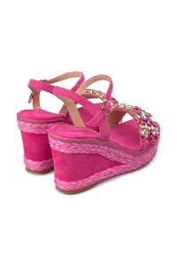 Sandales compensées en daim rose avec des détails tressés, embellies de gemmes colorées, dotées d'une sangle de cheville sécurisée et d'un design à bout ouvert.