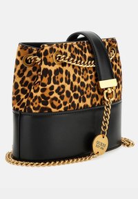 Bolso de tela con estampado de leopardo y base de cuero negro, con adornos de cadena dorada y etiqueta de logo dorada. Presenta una forma de cubo estructurada.