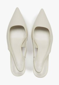 Beżowe szpilki typu slingback z ostrym noskiem, wyciętymi bokami i gładką, matową teksturą. Charakteryzują się minimalistycznym wzornictwem i wyściełaną wkładką.