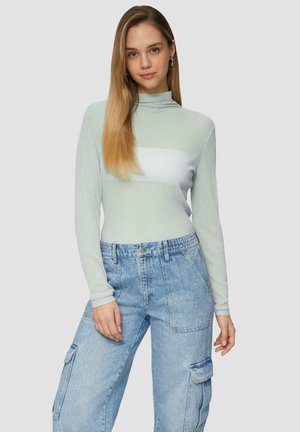 Haut à col roulé rayé de couleur vert clair avec des manches longues, doté d'une rayure horizontale blanche. Assorti à un pantalon cargo en denim bleu à taille haute.