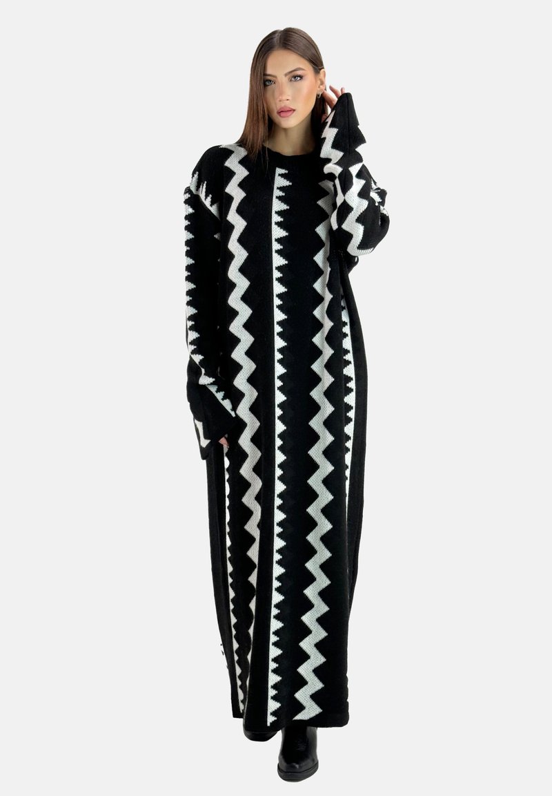 Abito lungo in maglia nera con un motivo a zigzag bianco, maniche ampie e una vestibilità rilassata, adatto per essere indossato a strati o da solo.