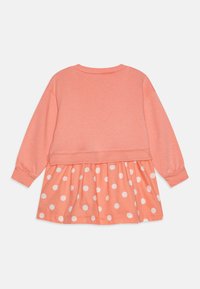 Two-piece outfit featuring a coral top and a polka dot skirt in matching coral and white. The top has long sleeves and a relaxed fit.