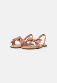 Sandali in tessuto rosa con dettaglio a fiocco annodato, design open-toe e suola beige. Presentano un aspetto minimalista con fasce posteriori per il supporto.