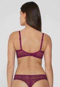 Lace bralette and matching thong in deep burgundy. Features adjustable straps, a hook closure, and floral lace pattern with scalloped edges.
