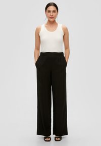 Zwarte wijde broek met een hoge elastische tailleband, gecombineerd met een aansluitend wit tanktop. Gladde stof, casual ontwerp, minimale accenten.
