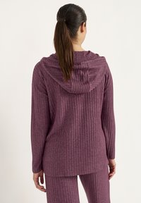 Paarse ribbel-langermouw top met een capuchon, met een relaxte pasvorm en een zachte textuur. Zichtbare naden en subtiele gemêleerde details.
