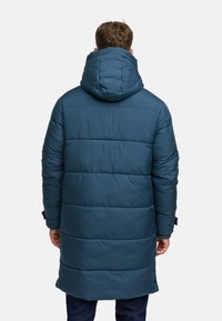 Cappotto imbottito con cappuccio in blu scuro, caratterizzato da segmenti trapuntati orizzontali, polsini regolabili e un design di lunghezza intermedia. Tessuto liscio.