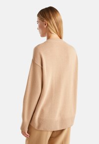 Beige oversized trui gemaakt van zacht breimateriaal, met een ribgebreide rand en manchetten, met een ontspannen silhouet en ronde halslijn.