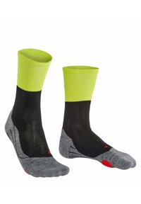 Chaussettes noires et vert fluo arrivant à la cheville avec des accents gris. Elles comportent des orteils renforcés, des semelles texturées et un ajustement serré.