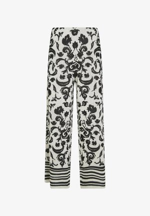 Pantaloni a gamba larga in maglia con motivo floreale nero e motivi a spirale su sfondo bianco, con righe orizzontali nere e bianche all'orlo.