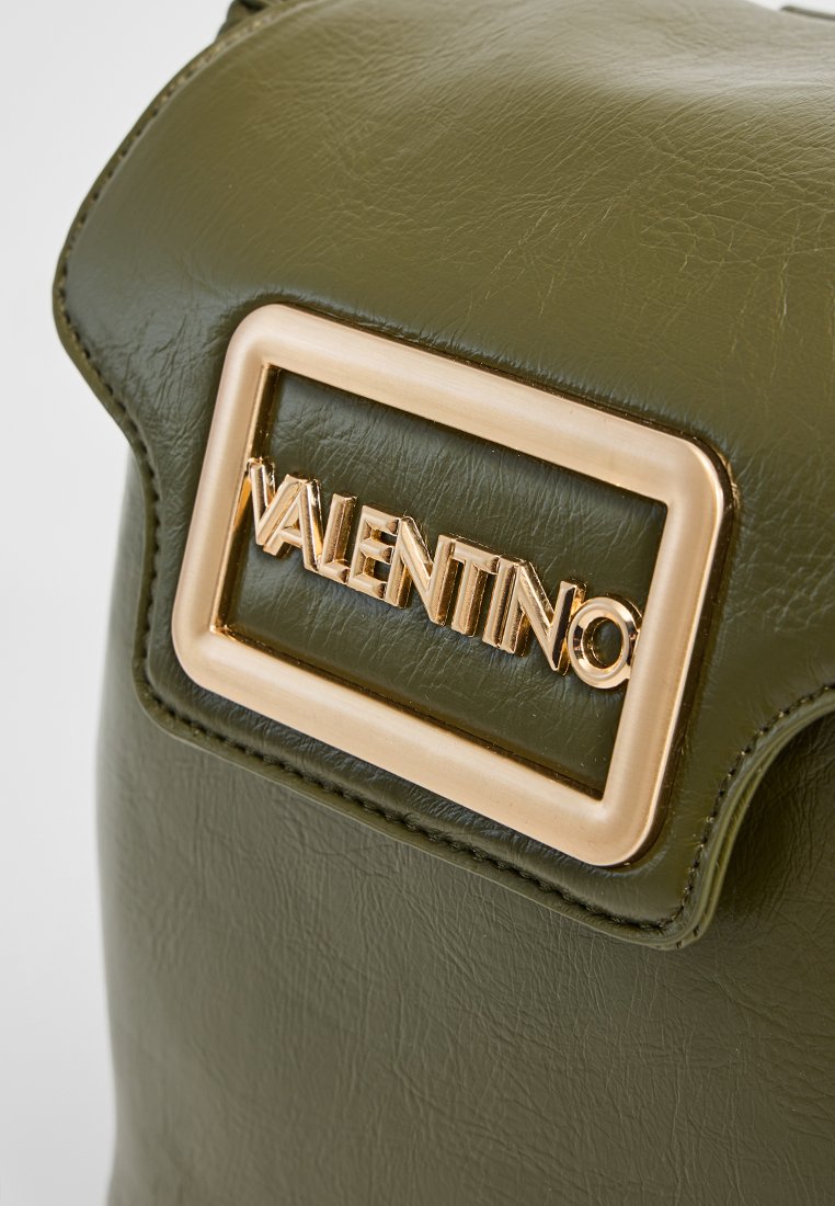 Grüne Lederhandtasche mit strukturiertem Format, ausgestattet mit einer goldenen rechteckigen Logo-Plakette, auf der "Valentino" steht. Glatte Textur.