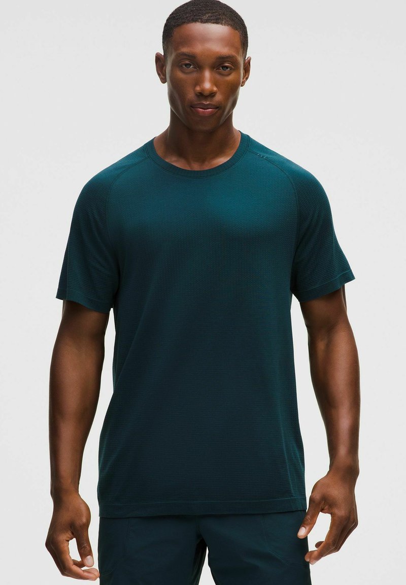 Sötét kékszürke, rövid ujjú sportpóló, kerek nyakkivágással, texturált anyagból, megerősített vállvarrással. Egyszerű dizájn, minták vagy díszítések nélkül.