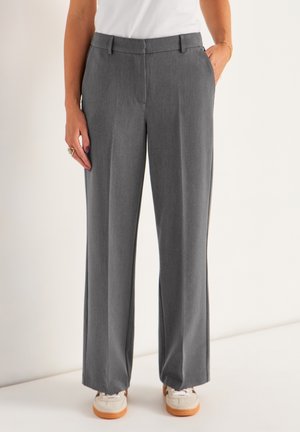 Grijze wijde broek gemaakt van een gestructureerde stof, met een platte voorkant, zijzakken en een getailleerde tailleband. Draag met witte sneakers.