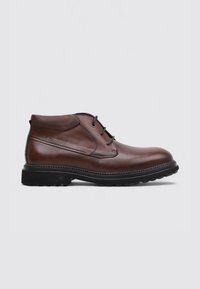 Bruine leren enkelboot met een gestructureerde kraag, vetersluiting, robuuste zwarte zool en contrasterende stikdetails.