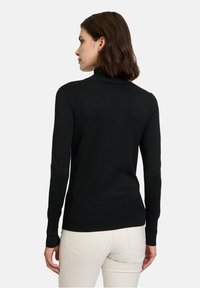Schwarzer Rollkragenpullover mit langen Ärmeln und tailliertem Schnitt, aus weichem Stoff gefertigt. Verfügt über gerippte Akzente am Kragen und Saum.