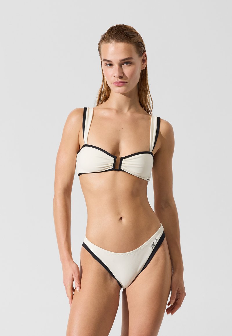 Bikini crème et noir avec un haut bandeau structuré à bretelles réglables et un bas taille haute coupé, confectionné en tissu texturé.