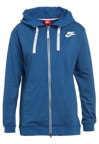 Blå ziptröja i mjuk bomullsblandning. Har en justerbar huva, ribbade ärmslut och framfickor. Nike-logotypen visas på bröstet.