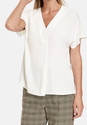 Weißes Kurzarmbluse mit V-Ausschnitt, mit einem lockeren Schnitt und einer subtilen Textur. Der Stoff fällt weich und hat einen leichten Glanz.