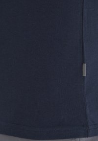 Tumši zilas krāsas kokvilnas T-krekls ar ribotām tekstūrām, ar nelielu svītrotu etiķeti sānu šuvē un taisnu apakšmalu.