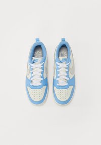 Baskets Nike avec un dessus bleu clair, des accents gris et des lacets blancs. Texture lisse avec des détails de boîte à orteils perforée et d'onglet de talon.