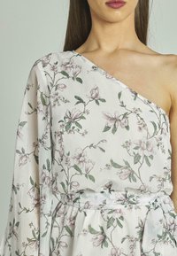 Weißes Kleid mit floralem Muster in Pink und Grün. Ein-Schulter-Design, lange fließende Ärmel, gebundene Taillendetails, strukturierter Stoff.