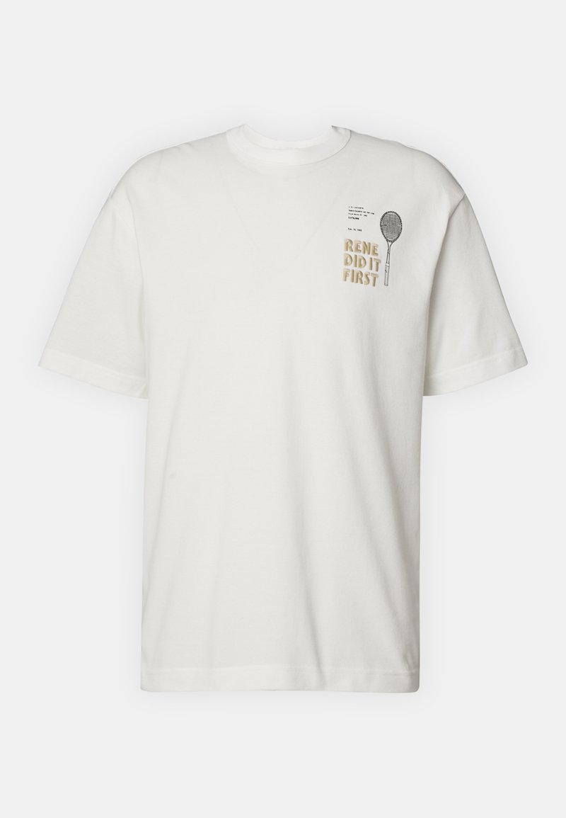 T-shirt bianca a maniche corte con una piccola grafica di una racchetta da tennis e la scritta "RENE L'HA FATTO PER PRIMO" sul lato sinistro del petto.