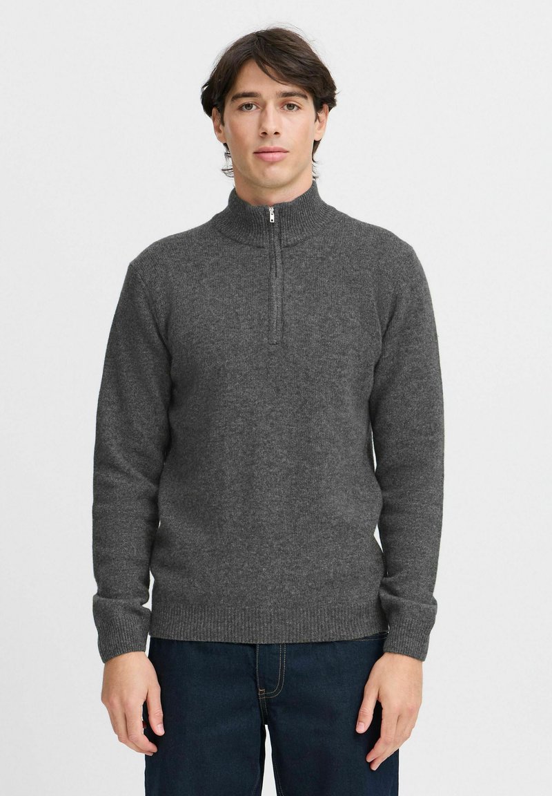 Sweater gri cu fermoar și guler înalt, realizat dintr-un material tricotat texturat. Mâneci și tiv ajustate, prezentat pe un model pe un fundal alb.