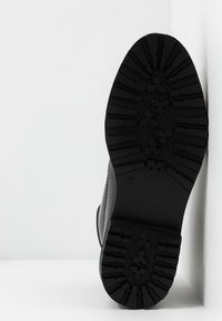 Semelle de botte en caoutchouc noir avec un motif de semelle profond, dotée d'une surface texturée et d'une inscription de taille 37 sur le côté.