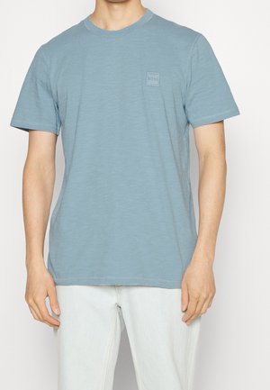 Lichtblauw T-shirt met korte mouwen van zacht materiaal. Voorzien van een klein vierkant logo op de borst en een ronde hals met gestikte details.