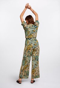 Conjunto relajado de estampado floral en verde y beige, con pantalones de pierna ancha y una blusa de manga corta, que cuenta con una tela texturizada.