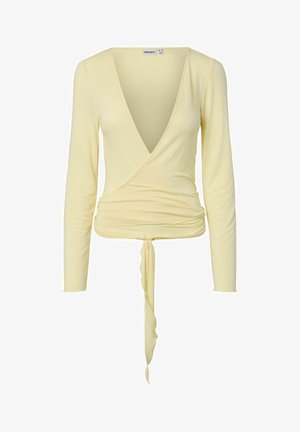 Bledo rumen dolg rokav zavijajoč top z globokim V-izrezom in detajlom vezave v pasu, padajočim materialom spredaj.