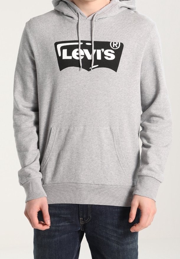 Persona vistiendo una sudadera ligera de Levi's en gris claro con un logo negro, con un bolsillo canguro frontal y capucha con cordones, combinada con unos jeans azul oscuro.