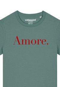 T-shirt en coton vert avec col rond, arborant le mot "Amore" en grandes lettres rouges centrées sur le devant. Texture douce, design décontracté.