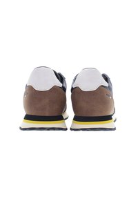 Scarpe sportive in pelle con tacco in suede marrone, parte superiore nera, accenti grigi, colletto bianco e dettagli gialli sulla suola.