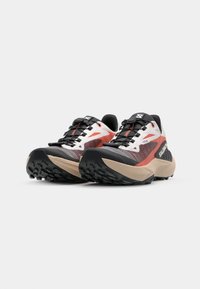Trail running shoes with a black, red, and white mesh upper, features a durable rubber sole, multiple lace hooks, and a textured grip pattern.