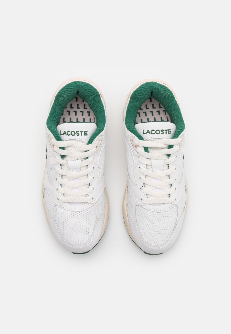 Zapatillas blancas con acentos y logotipo verdes, con una parte superior texturizada, puntera redonda, cierre con cordones y forro interior estampado.