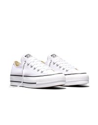 Paire de baskets Converse All Star basses blanches avec semelles plateformes épaisses à rayures noires et lacets blancs sur un fond blanc.
