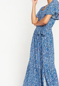 Modrá vzorovaná maxi šaty s hlubokým výstřihem do V, krátkými nafouknutými rukávy a nazbíraným pasem, s jemnými paisley a květinovými vzory.