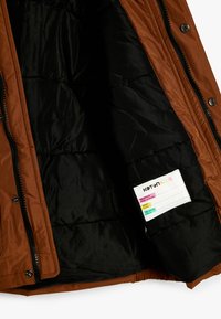 Brun pufferjakke med sort inderside, med lynlås front og en plejeetiket syet indeni. Glat stof med en quiltet tekstur.