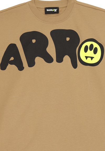 Maglietta a maniche corte di colore tan con grandi lettere nere che formano la scritta "ARRO" e un volto sorridente giallo con zanne, realizzata in morbido cotone.