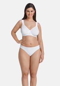 Reggiseno bianco con coppette morbide e spalline larghe, abbinato a slip bikini bianchi. Entrambi presentano una texture liscia e un design minimalista.