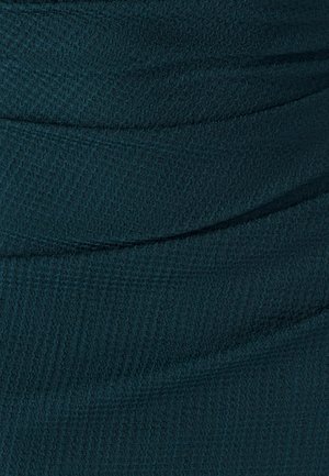 Teal värvusega tekstureeritud kangas horisontaalsete ribade ja õrnate mustritega, disainitud keha külge liibuvate rõivaste jaoks. Sile pind õige venivusega.