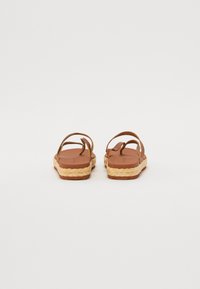 Sandali espadrillas marroni con cinturini intrecciati e suola texturizzata, dotati di un sottopiede in juta intrecciata e una zeppa piatta.