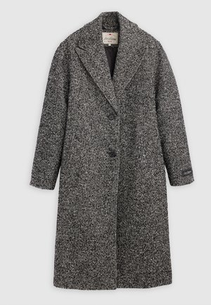 Juodos ir baltos spalvos vilnonis paltas su didelėmis houndstooth raštais, turintis išsišakojusį atvartą, dvi sagas ir vieną kišenę su prekės ženklo etikete ant rankovės.