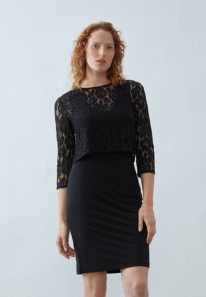 Black lace top with three-quarter sleeves paired with a fitted black dress. Smooth texture, intricate lace pattern, and sleek silhouette.