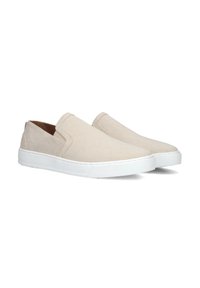 Beige instap schoenen van canvas met witte rubberen zolen, met een ronde neus en zonder zichtbare hardware of versieringen.